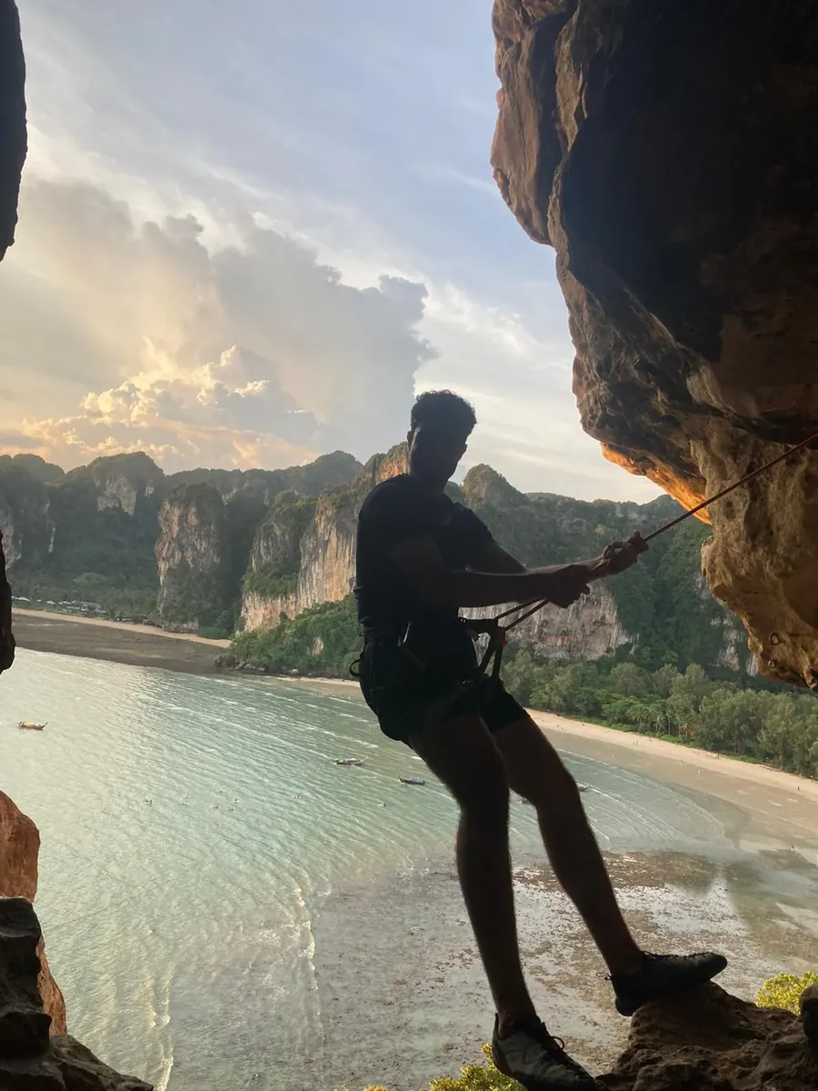 Rappelling down a sea cliff overlooking a limestone-cliff beach at sunset